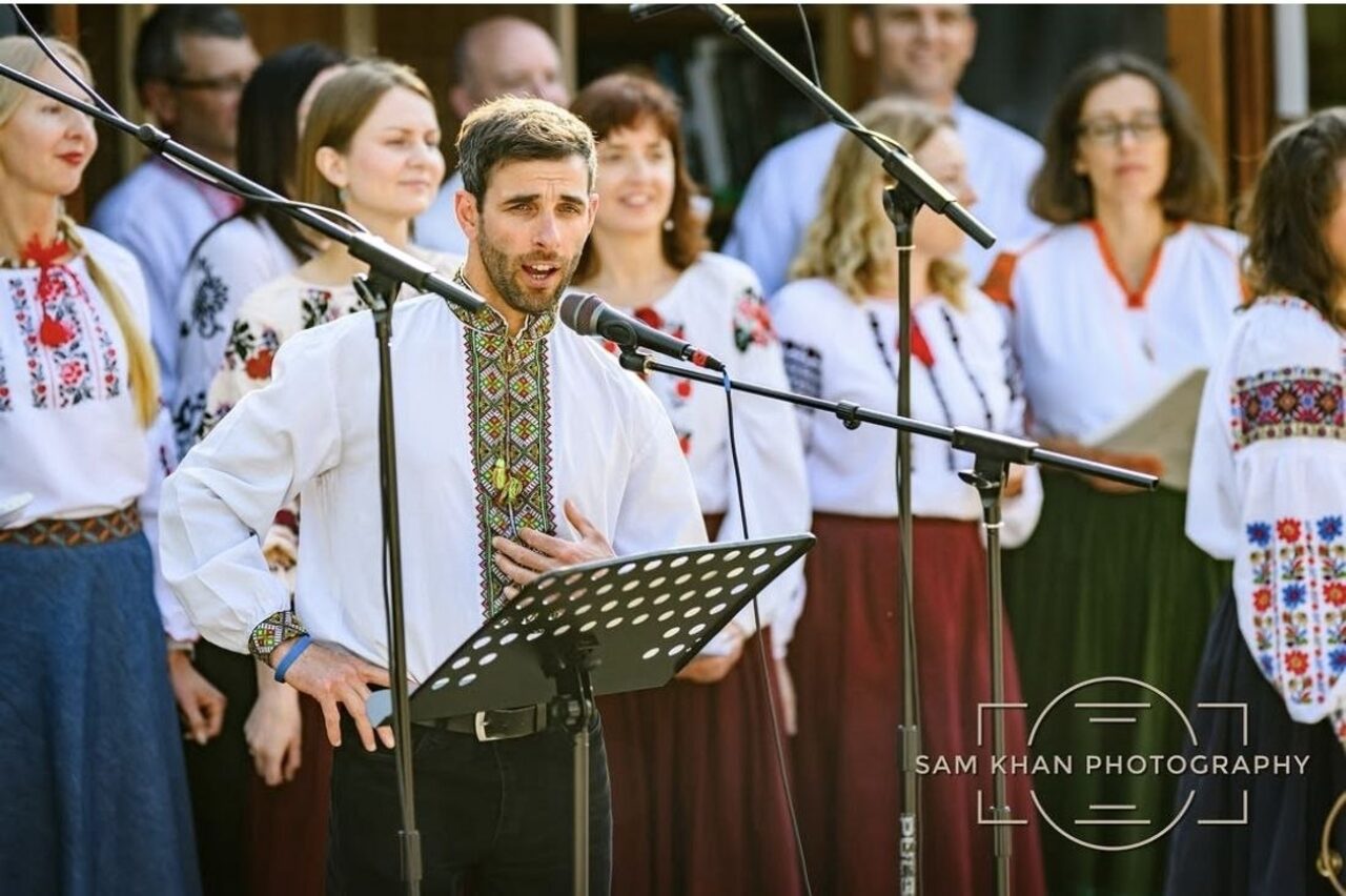 A soloist singing with Ukrainian Voices choir at an outdoor performance.
